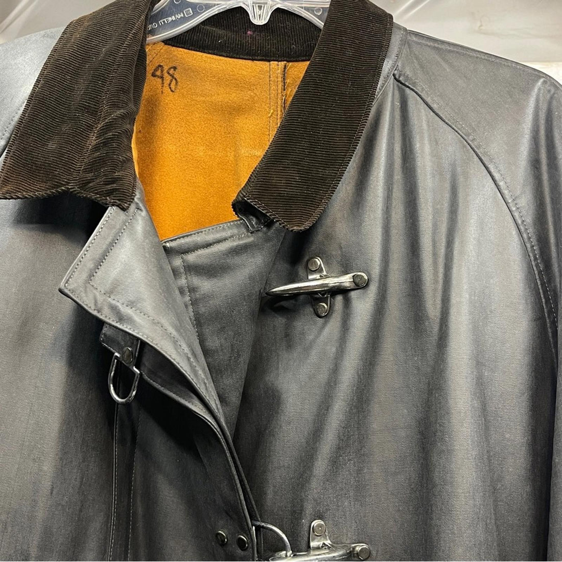 Gray Country Cowboy coat on a hanger with a mountainous landscape in the background